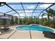 A relaxing screened-in pool area with a waterfall feature, lounge chairs, and lush tropical landscaping at 1053 Alcove Loop, The Villages, FL 32162