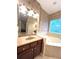 Elegant bathroom featuring a vanity, a luxurious soaking tub, and coordinated wall paper at 108 Whispering Pines Way, Davenport, FL 33837