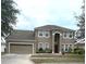 Well maintained two-story house with green grass, brown mulch, and a two car garage at 108 Whispering Pines Way, Davenport, FL 33837