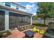 Backyard patio area with brick pavers, outdoor seating, and a screened-in patio at 1155 Dora Parc Ln, Mount Dora, FL 32757