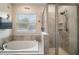 Bathroom boasts soaking tub, tiled walls, glass shower, and natural light from the window at 1155 Dora Parc Ln, Mount Dora, FL 32757