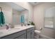 Bright bathroom with dual sinks, gray cabinets, and decorative mirror with recessed lighting at 1155 Dora Parc Ln, Mount Dora, FL 32757