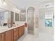 Bright bathroom featuring double sinks, walk-in shower, and decorative stained-glass window at 12118 Se 175Th Loop, Summerfield, FL 34491