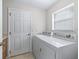 Bright laundry room featuring a white washer and dryer next to a door and window at 12118 Se 175Th Loop, Summerfield, FL 34491