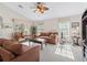 Bright living room with comfortable seating, ceiling fan, and natural light from large windows at 12118 Se 175Th Loop, Summerfield, FL 34491