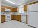 Functional kitchen with oak cabinets, white appliances, tile floors and bright overhead lighting at 13875 Se 97Th Ave, Summerfield, FL 34491