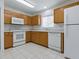 Functional kitchen with oak cabinets, white appliances, tile floors and bright overhead lighting at 13875 Se 97Th Ave, Summerfield, FL 34491