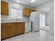 Functional kitchen featuring oak cabinets, white appliances, tile flooring, and a bright window at 13875 Se 97Th Ave, Summerfield, FL 34491