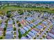 Overhead view of a peaceful residential area featuring cozy homes, a tranquil lake, and green surroundings at 1722 Moreno Pl, The Villages, FL 32159