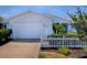 Charming one-story home featuring a white picket fence, palm trees, and well-manicured landscaping at 1722 Moreno Pl, The Villages, FL 32159