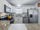 Well-lit kitchen with stainless steel appliances, granite counters, white cabinetry, and modern fixtures at 1722 Moreno Pl, The Villages, FL 32159