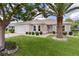 Inviting single-story home featuring a well-manicured lawn, a two-car garage, and lovely landscaping at 1813 Caryle Ln, The Villages, FL 32162