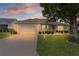 Charming single-story home with a well-maintained lawn and a two-car garage at sunset at 1813 Caryle Ln, The Villages, FL 32162