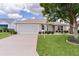 Charming single-story home featuring a two-car garage, lush lawn, and beautiful landscaping at 1813 Caryle Ln, The Villages, FL 32162