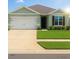 Inviting single-story home featuring a two-car garage, a well-manicured lawn, and charming architectural details at 2106 Elio Ridge Dr, Zellwood, FL 32798