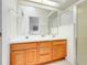 Bright bathroom with double sinks, a large mirror, tile floors, and a glass-enclosed shower at 21226 Royal St Georges Ln, Leesburg, FL 34748