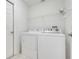 Bright laundry area with a washer, dryer, wire shelving, and a tiled floor at 21226 Royal St Georges Ln, Leesburg, FL 34748