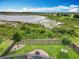 Serene backyard overlooking a lake, showcasing an iron fence, mature trees, and a cozy brick patio with firepit at 224 Silver Maple Rd, Groveland, FL 34736