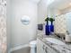 Stylish half bathroom features a granite countertop and decorative ocean artwork at 224 Silver Maple Rd, Groveland, FL 34736