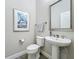 Neutral half bath with pedestal sink, gray tile floor, and decorative framed artwork at 224 Silver Maple Rd, Groveland, FL 34736