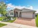 Charming home with stone archway, brick driveway, and fresh landscaping under a bright blue sky at 224 Silver Maple Rd, Groveland, FL 34736