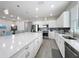 Bright kitchen boasts white cabinets, stainless steel appliances, and a large center island with a quartz countertop at 224 Silver Maple Rd, Groveland, FL 34736