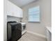 Clean laundry room with upper cabinets and modern black and white washer and dryer at 224 Silver Maple Rd, Groveland, FL 34736