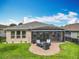 Back exterior of home features a screened in porch and brick patio with ample lawn space and beautiful landscaping at 224 Silver Maple Rd, Groveland, FL 34736