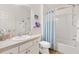 Bright bathroom featuring a vanity with a white sink and cabinets, a toilet, and a shower with a blue curtain at 2457 Upton St, The Villages, FL 32163