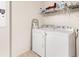 Functional laundry room with a white washer and dryer, plus shelving for storage and a metal step ladder at 2457 Upton St, The Villages, FL 32163
