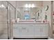 Well-lit bathroom with dual sinks, white cabinets, large mirror, and glass-enclosed shower at 27215 White Plains Way, Leesburg, FL 34748