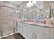 Well-lit bathroom with dual sinks, granite countertops, white cabinets, and a glass-enclosed shower at 27215 White Plains Way, Leesburg, FL 34748