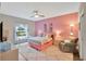 Charming bedroom with a pink accent wall, cozy furnishings, soft lighting, and a serene view from the window at 27215 White Plains Way, Leesburg, FL 34748