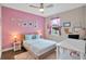 Bright bedroom featuring a pink accent wall, cozy furnishings, soft lighting, and a serene view from the window at 27215 White Plains Way, Leesburg, FL 34748