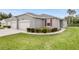 A modern one-story home with a gray exterior, two-car garage, and a well-manicured lawn with shrubbery at 27215 White Plains Way, Leesburg, FL 34748