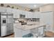 Bright kitchen with stainless steel appliances, a gray countertop island with seating, and white cabinetry at 27215 White Plains Way, Leesburg, FL 34748