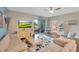 Comfortable living room with neutral furniture, ceiling fan, television, and view of a screened outdoor patio at 27215 White Plains Way, Leesburg, FL 34748