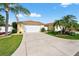 Expansive driveway leading to a two-car garage, complemented by lush landscaping and palm trees at 2744 Gresham Ave, The Villages, FL 32162