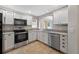 Well-lit kitchen featuring stainless steel appliances, granite countertops and white cabinets at 2744 Gresham Ave, The Villages, FL 32162
