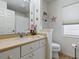 Well-lit bathroom features a vanity with sink, toilet, large mirror, and shelving at 3001 Lake Huron Ln, Tavares, FL 32778