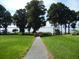 Scenic view with manicured lawns, mature trees, and a pathway leading to the water's edge at 3001 Lake Huron Ln, Tavares, FL 32778