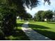 A winding walkway meanders through a beautifully landscaped green lawn and mature trees under a bright sky at 3001 Lake Huron Ln, Tavares, FL 32778