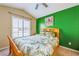 Bright bedroom features a vaulted ceiling, a palm tree-themed comforter set, and a green accent wall at 310 Ballyshannon Dr, Davenport, FL 33897