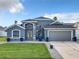 Beautiful blue two-story home featuring manicured lawn, a two-car garage, and modern architectural details at 310 Ballyshannon Dr, Davenport, FL 33897