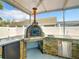 Well-equipped outdoor kitchen with brick pizza oven, countertop, and stainless steel fridge in a covered patio at 310 Ballyshannon Dr, Davenport, FL 33897