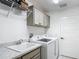 Well-lit laundry room with gray cabinets, marble countertop, utility sink, and white appliances at 3138 Aurea Pl, The Villages, FL 32163