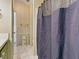 Tiled bathroom with a blue shower curtain and neutral-toned wallpaper at 32521 W Golf Ct, Leesburg, FL 34748