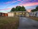 Charming home featuring an enclosed porch and a well-maintained lawn under a beautiful sunset sky at 32521 W Golf Ct, Leesburg, FL 34748