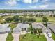 Expansive aerial view of community with lush landscaping, golf course, and single-story homes under a partly cloudy sky at 3677 Arlington Ridge Blvd, Leesburg, FL 34748
