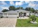 Charming home with a three-car garage, well-manicured lawn, and beautiful landscaping under a partly cloudy sky at 3677 Arlington Ridge Blvd, Leesburg, FL 34748
